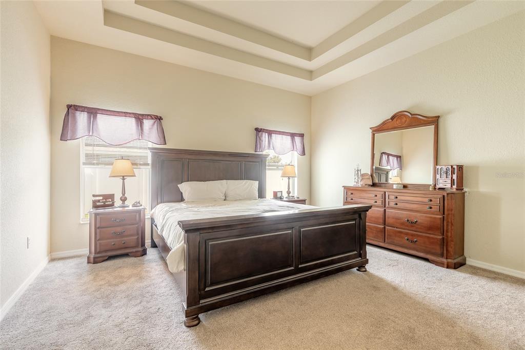 A bedroom features a dark wood bed frame, matching dresser with mirror, and carpeted flooring — 8 LAMOYNE LANE, PALM COAST, FL