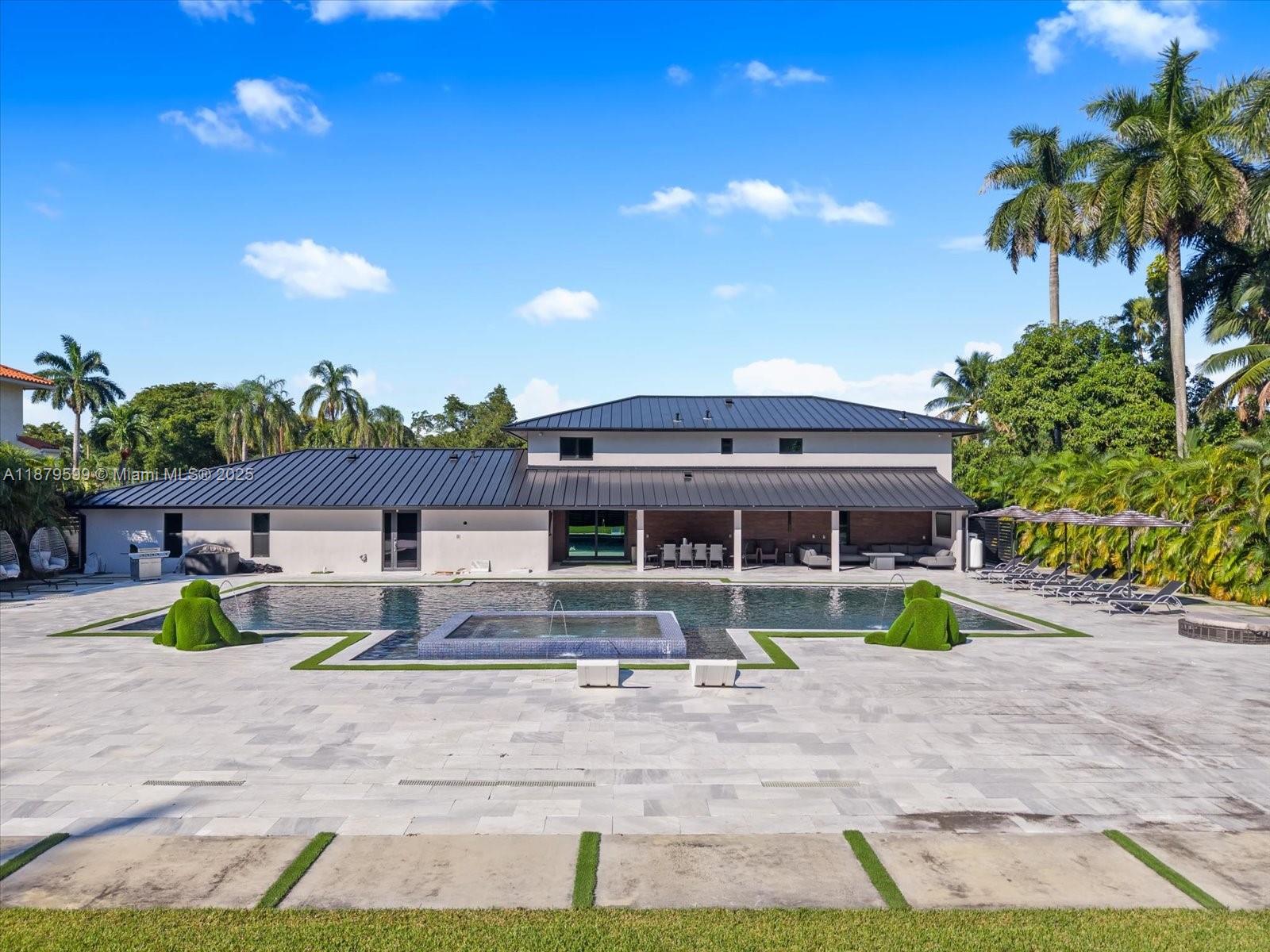 A large house with a dark metal roof overlooks a swimming pool and patio area — 280 NE 156th St, Miami FL 33162, MIAMI, FL