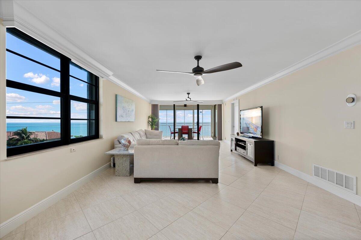 A living room with light tile floors, a white sofa, and a view of the ocean — 911 Ocean Drive # 506, North Palm Beach FL 33408, NORTH PALM BEACH, FL