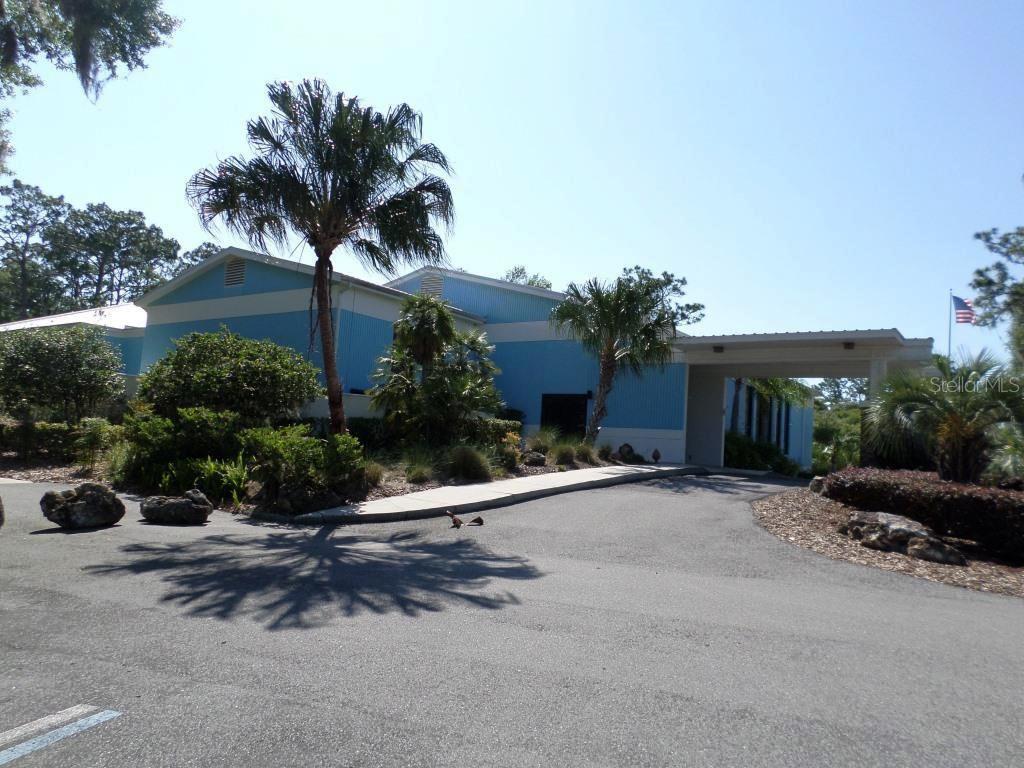 A blue building with a covered entrance and palm trees sits next to a paved driveway — 8518 SW 189TH COURT RD, DUNNELLON, FL