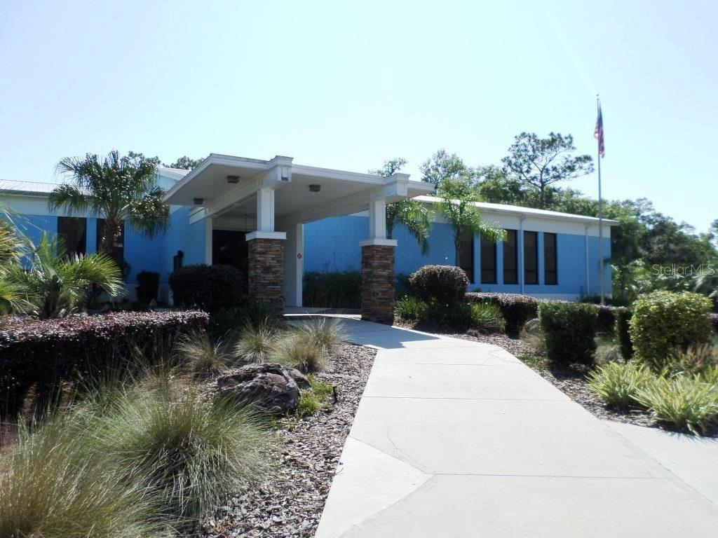 A blue building with a stone-columned covered entrance and a concrete walkway leading to it — 8518 SW 189TH COURT RD, DUNNELLON, FL