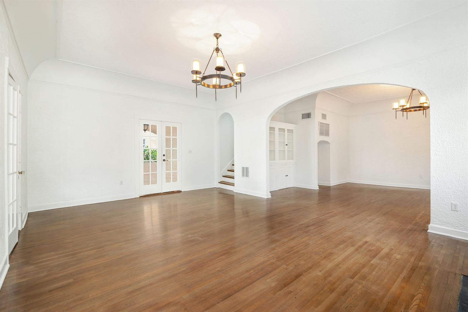 An empty room with hardwood floors, a chandelier, and an arched opening to another space — 232 Rugby Road, West Palm Beach FL 33405, WEST PALM BEACH, FL