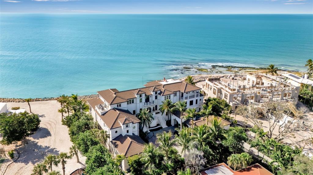 An aerial view shows a large multi-story coastal villa next to a construction site — 7366 POINT OF ROCKS ROAD, SARASOTA, FL