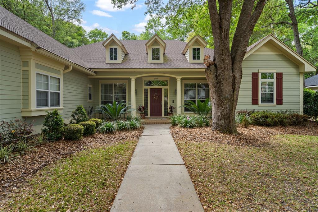 A single-story house with light green siding, a red front door, and three roof dormers — 3212 SW 98TH DRIVE, GAINESVILLE, FL