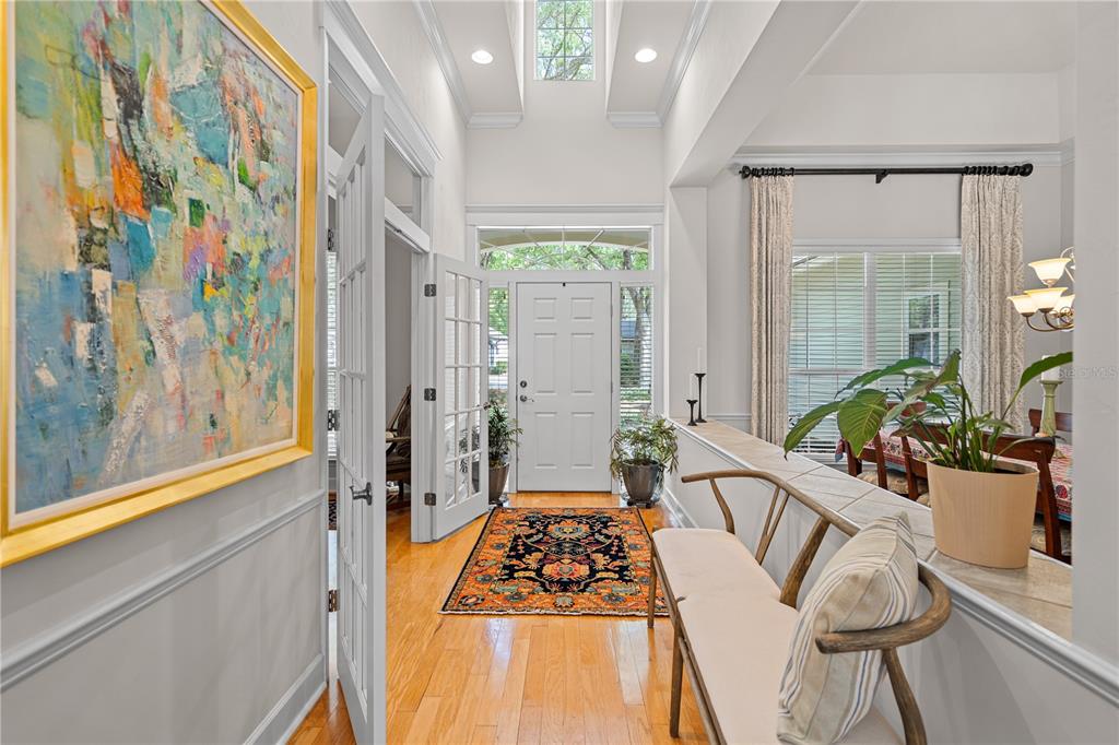 A bright entryway features hardwood floors, a colorful area rug, and a bench near stairs — 3212 SW 98TH DRIVE, GAINESVILLE, FL