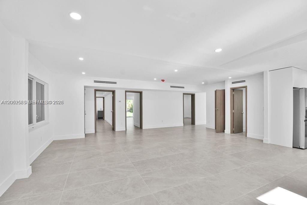 A spacious, minimalist room features white walls, recessed lighting, and large light-gray floor tiles — 7902 SW 67th Ave # 0, South Miami FL 33143, SOUTH MIAMI, FL