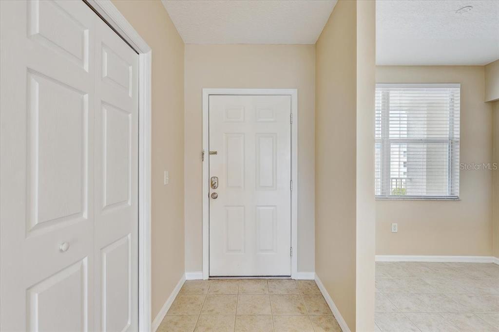 An entryway features a tiled floor, a white front door, and a closet door — 1200 COUNTRY CLUB DRIVE UNIT 3405, LARGO, FL
