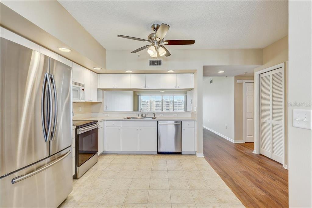 A kitchen features white cabinets, stainless steel appliances, tile flooring, and a ceiling fan — 1200 COUNTRY CLUB DRIVE UNIT 3405, LARGO, FL