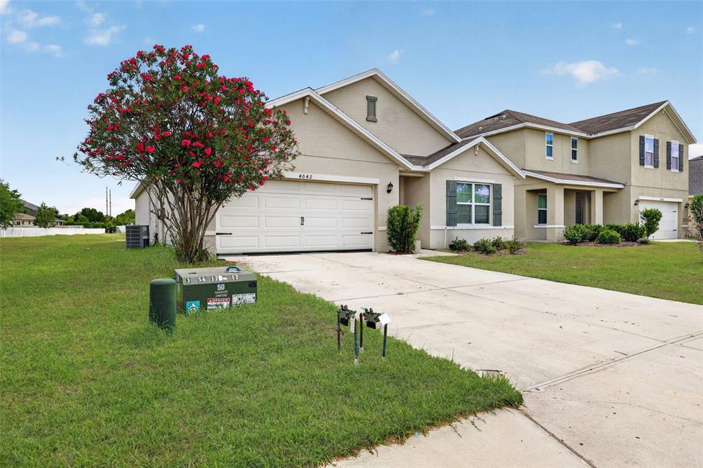 A single-story suburban house with a two-car garage and a blooming crepe myrtle tree — 4042 WAYFARER WAY, PALMETTO, FL