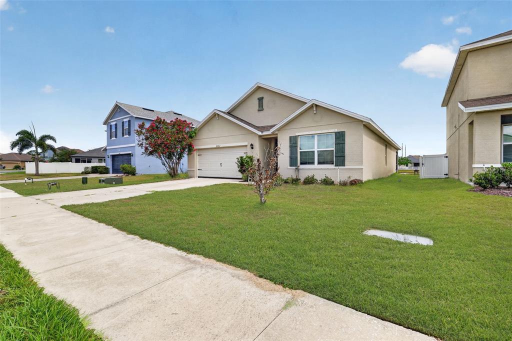 A single-story suburban house with a tan exterior, a two-car garage, and a front lawn — 4042 WAYFARER WAY, PALMETTO, FL