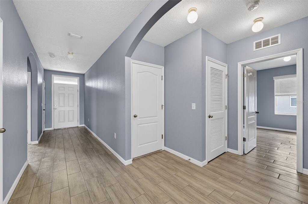 A hallway with light blue walls, wood-look tile flooring, and several white interior doors — 4042 WAYFARER WAY, PALMETTO, FL