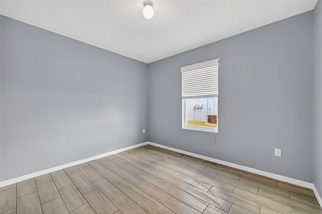 An empty bedroom features gray walls, wood-look tile flooring, and a single window with blinds — 4042 WAYFARER WAY, PALMETTO, FL