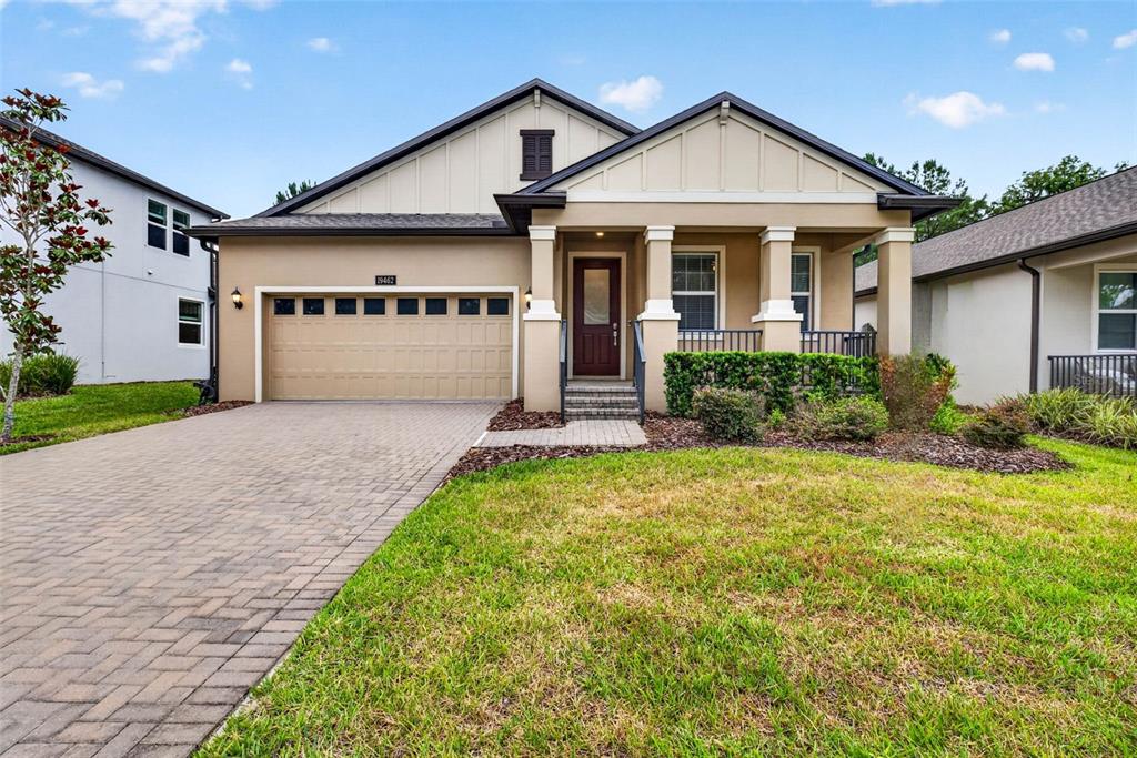 A single-story house with a tan exterior, a paved driveway, and a covered front porch — 19462 FOREST GARDEN COURT, BROOKSVILLE, FL