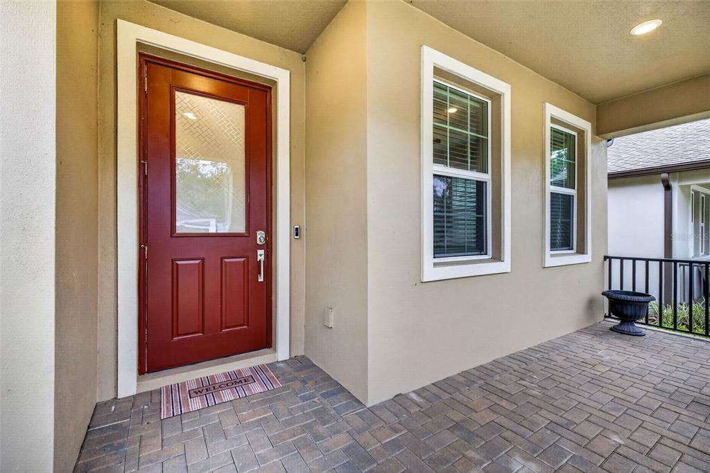A red front door with a glass panel sits on a paved porch — 19462 FOREST GARDEN COURT, BROOKSVILLE, FL