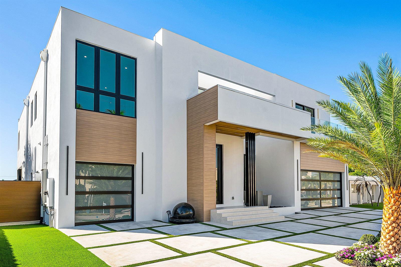 A modern two-story house with white stucco, wood paneling, glass garage doors, and a palm tree — 750 NE 69th Street, Boca Raton FL 33487, BOCA RATON, FL