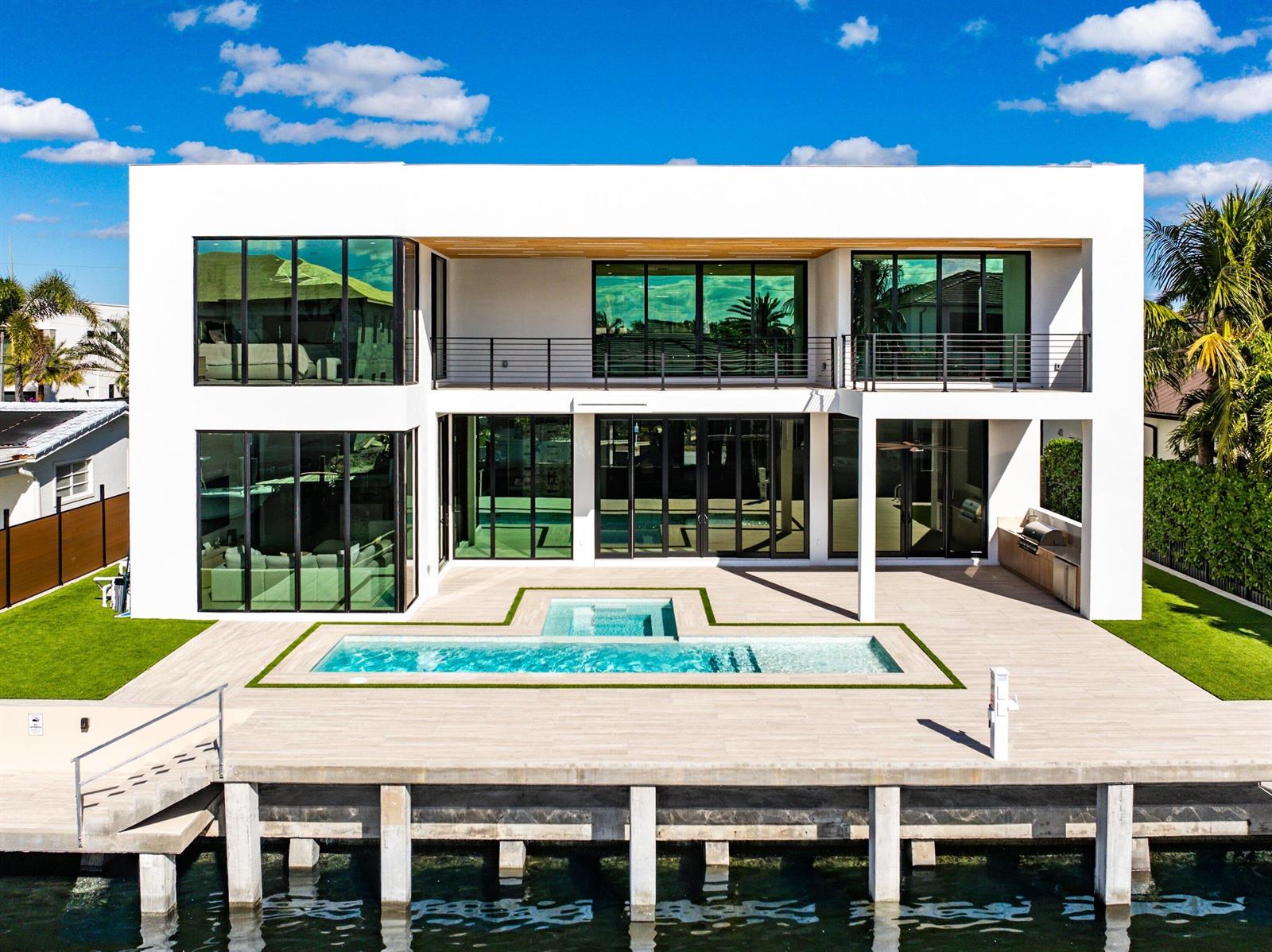 A modern two-story white house with a pool, patio, and dock overlooking the water — 750 NE 69th Street, Boca Raton FL 33487, BOCA RATON, FL