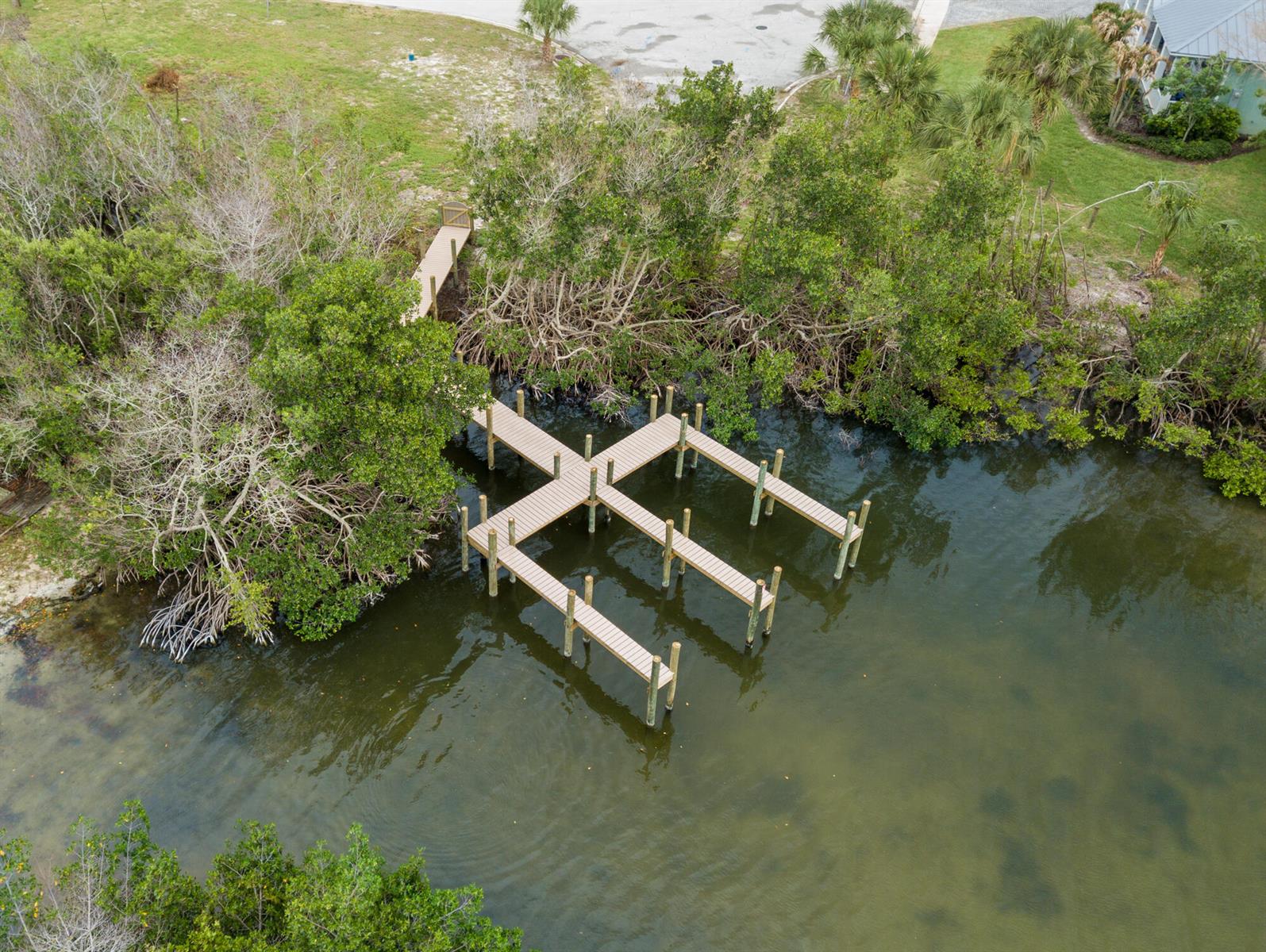 A wooden boat dock extends into a calm body of water surrounded by mangrove trees — 1540 Outer Drive, Merritt Island FL 32952, MERRITT ISLAND, FL