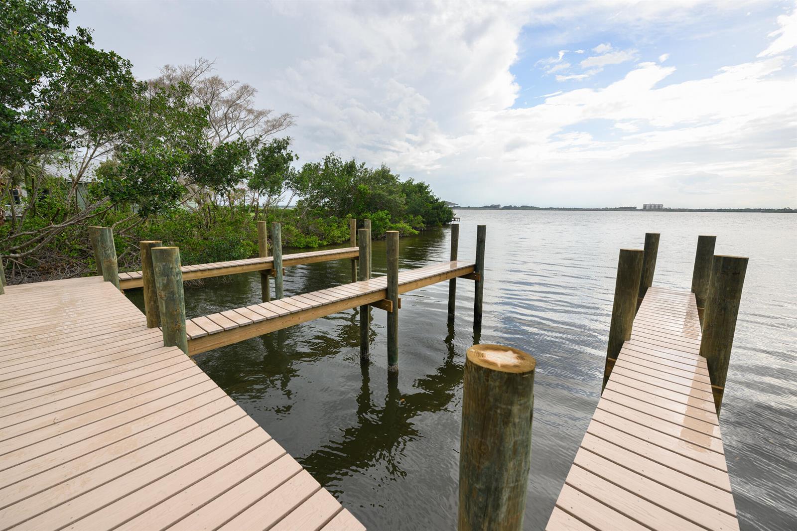 An aerial view shows a wooden boat dock extending from a shoreline into the water — 1540 Outer Drive, Merritt Island FL 32952, MERRITT ISLAND, FL