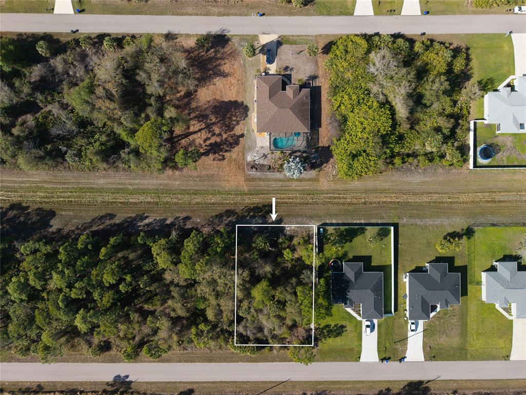 An aerial view shows a vacant, wooded residential lot outlined in white between two houses — Lot 6 SAWYER CIRCLE, NORTH PORT, FL
