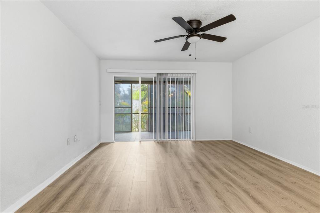 An empty room with light wood-look flooring, a ceiling fan, and sliding glass patio doors — 6800 PLACIDA ROAD UNIT 132, ENGLEWOOD, FL