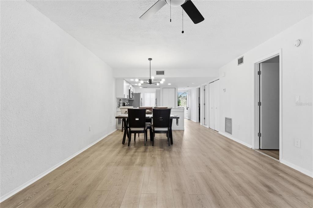 An open-concept dining area features light wood-look flooring, white walls, and a modern chandelier — 6800 PLACIDA ROAD UNIT 132, ENGLEWOOD, FL