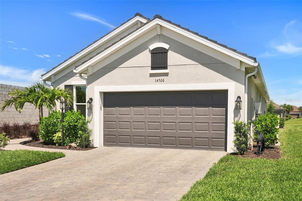 The exterior of a single-story house features a two-car garage and a paved driveway — 14506 DERNA TERRACE, BRADENTON, FL