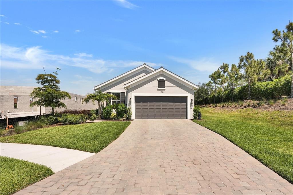 A single-story house with a gray garage and a paved driveway under a blue sky — 14506 DERNA TERRACE, BRADENTON, FL