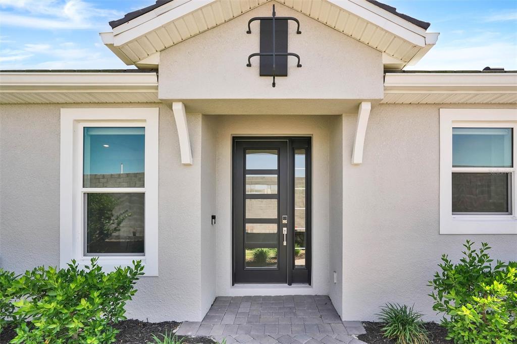 The exterior of a house features a dark front door with glass panels and windows — 14506 DERNA TERRACE, BRADENTON, FL