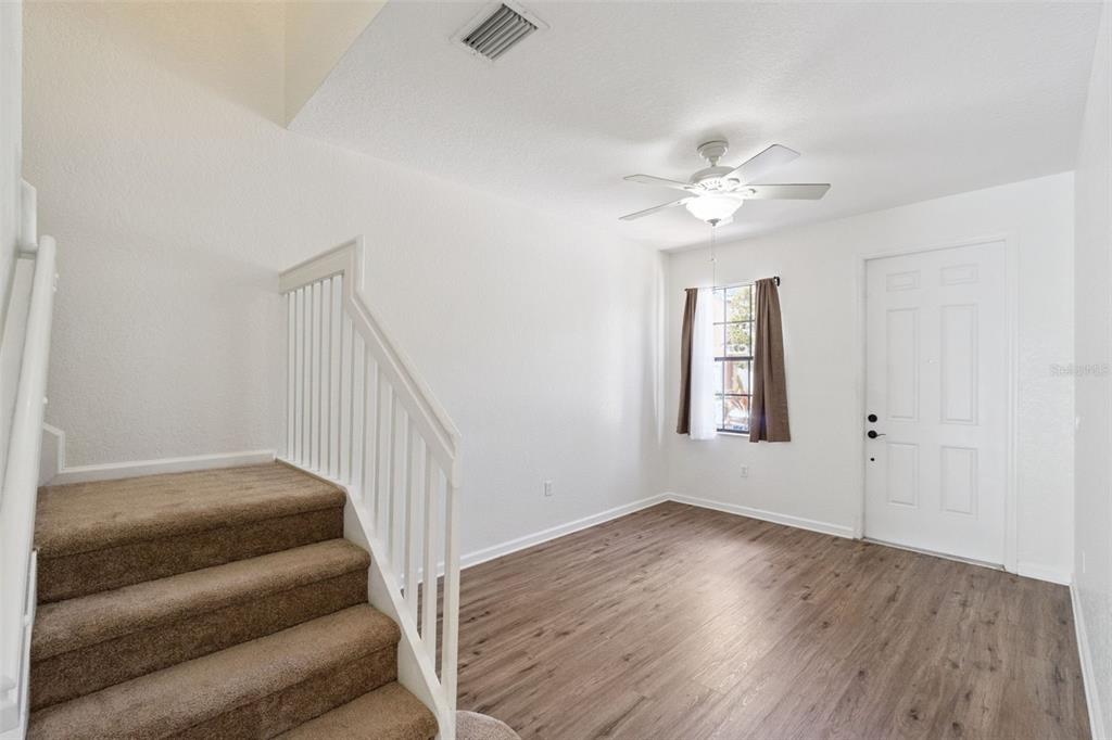 A room with wood-look flooring, carpeted stairs with a white railing, and a ceiling fan — 3491 ALLEGRA CIRCLE, ST CLOUD, FL