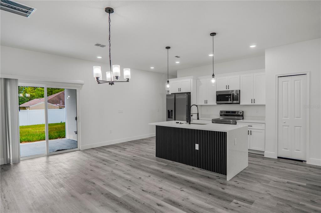 A modern kitchen features white cabinetry, a black slatted island, and gray wood-look flooring — 1948 W ADELIA PLACE, CITRUS SPRINGS, FL