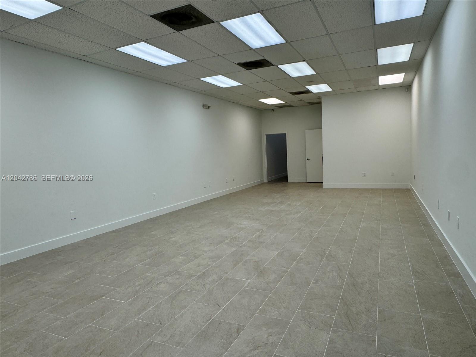 An empty commercial room features white walls, a drop ceiling with recessed lights, and tile flooring — 4005 NW 114th Ave # 09, Doral FL 33178, DORAL, FL