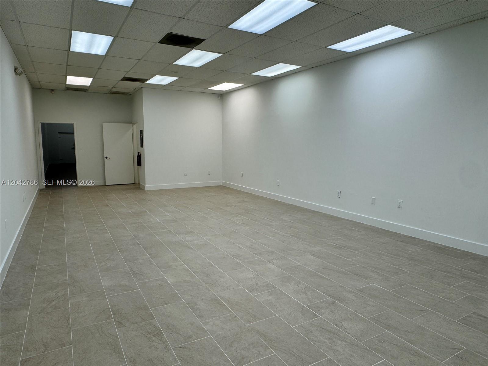 An empty commercial space features white walls, a drop ceiling with recessed lights, and tiled floors — 4005 NW 114th Ave # 09, Doral FL 33178, DORAL, FL