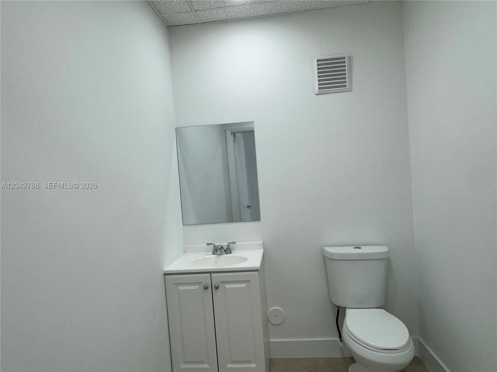 A small bathroom features a white vanity with a sink, a mirror, and a toilet — 4005 NW 114th Ave # 09, Doral FL 33178, DORAL, FL