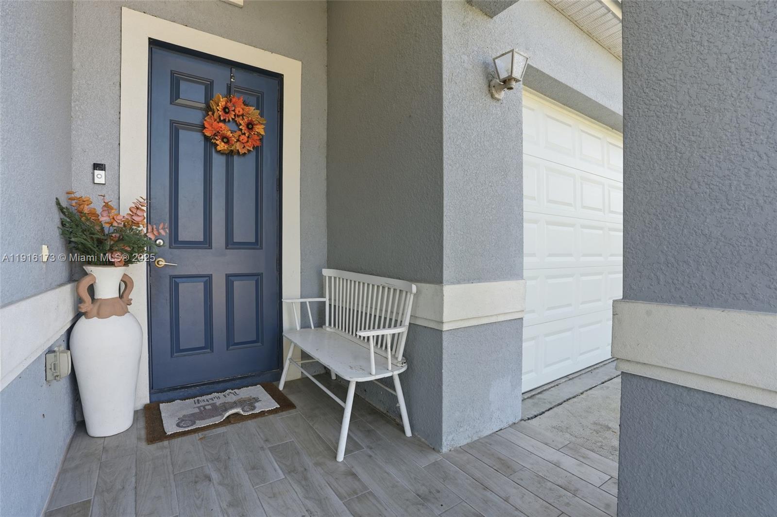 A blue front door with a wreath, a white bench, and a large vase — OTHER CITY - IN THE STATE OF FLORIDA, FL
