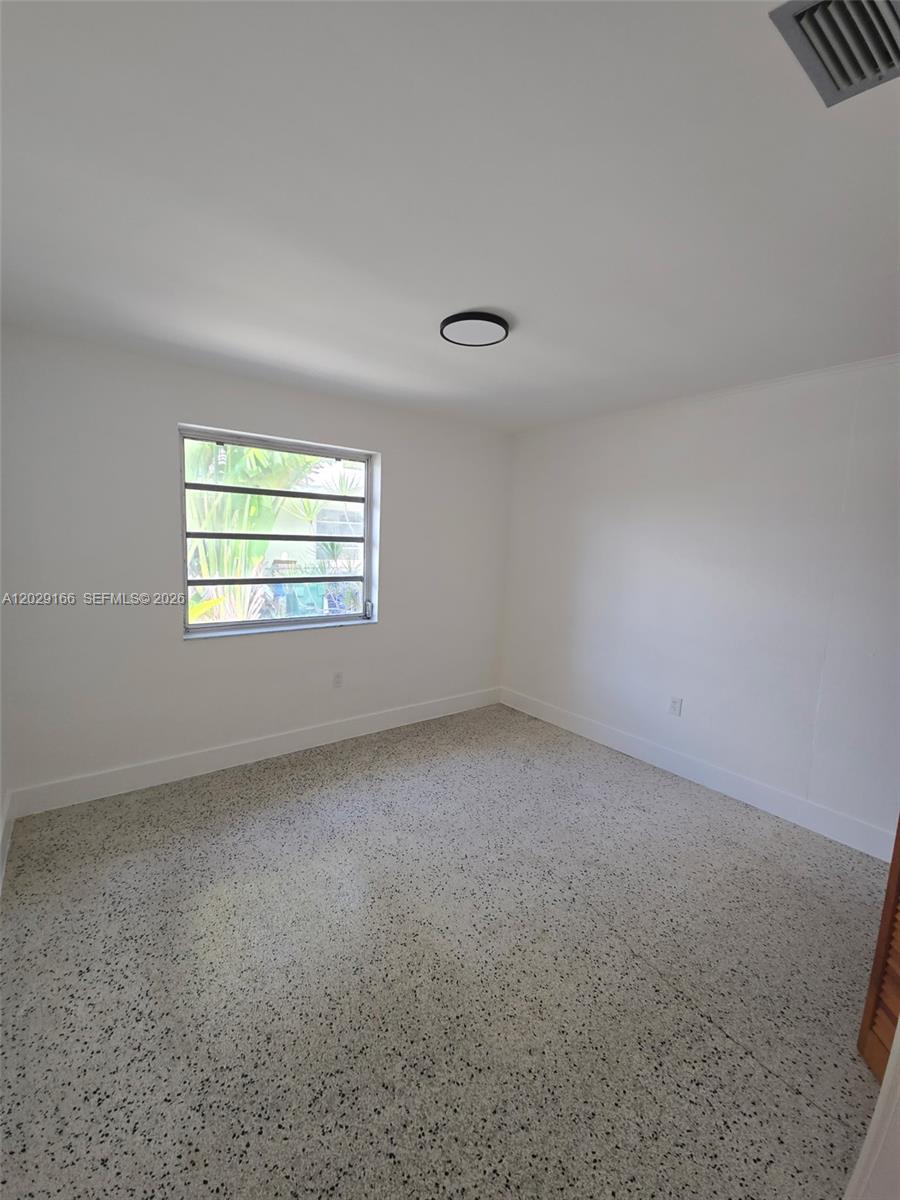 An empty bedroom features white walls, a single window, and speckled terrazzo flooring — 3435 NW 4th St, Miami FL 33125, MIAMI, FL