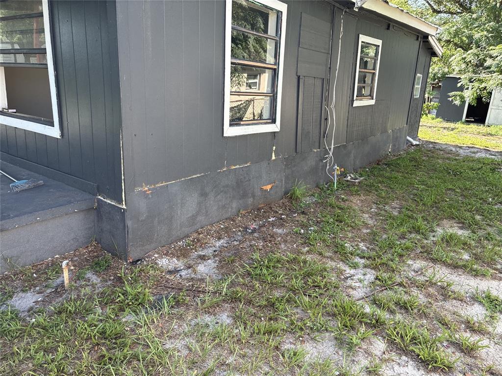 The exterior of a dark gray house shows a concrete foundation, windows, and siding — 10529 3RD AVENUE, OCOEE, FL