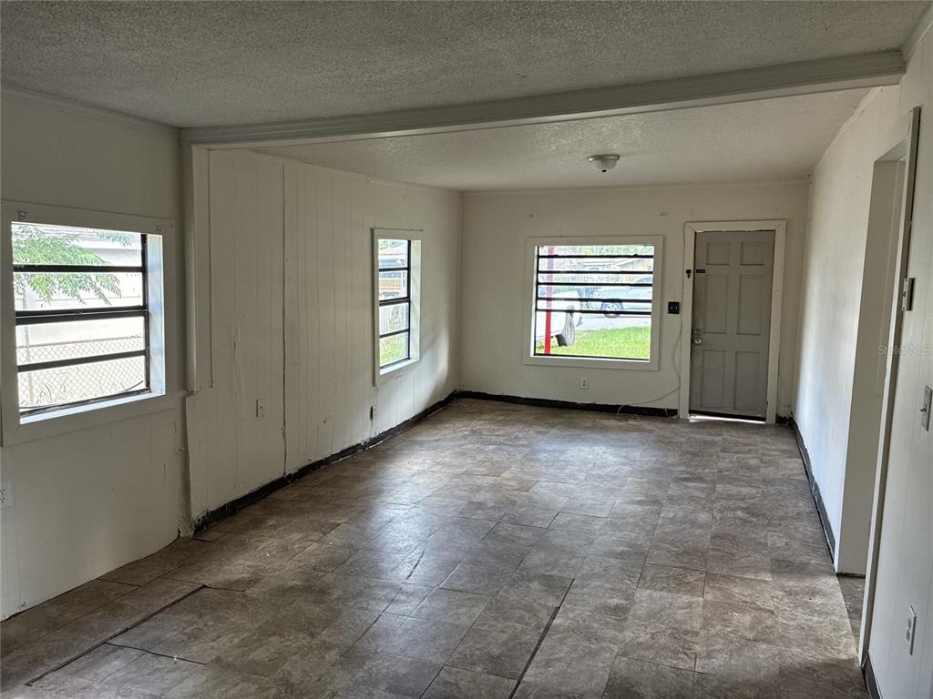An empty room with tiled floors, white paneled walls, and several windows — 10529 3RD AVENUE, OCOEE, FL