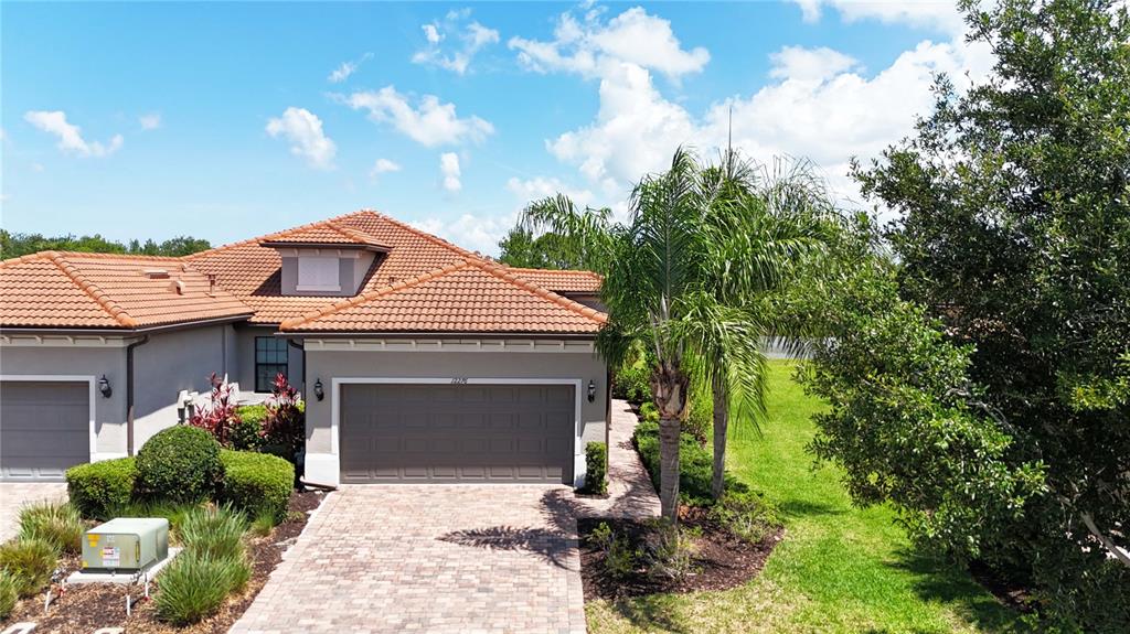 An exterior view of a house with a tiled roof, garage, and a palm tree — 12276 MARSH POINTE ROAD, SARASOTA, FL