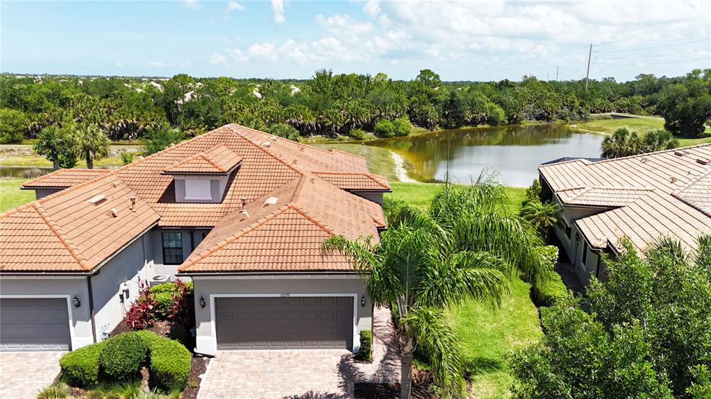 An aerial view of a suburban house with a tiled roof and a nearby pond — 12276 MARSH POINTE ROAD, SARASOTA, FL