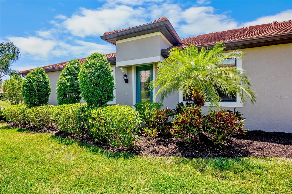 A single-story house exterior features a tiled roof, a front entrance, and landscaped garden beds — 12276 MARSH POINTE ROAD, SARASOTA, FL