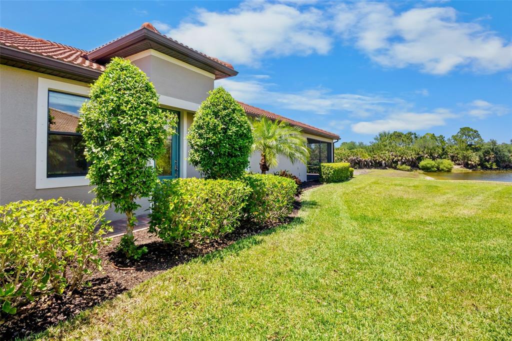 A view of the side of a house with landscaping and a grassy yard — 12276 MARSH POINTE ROAD, SARASOTA, FL
