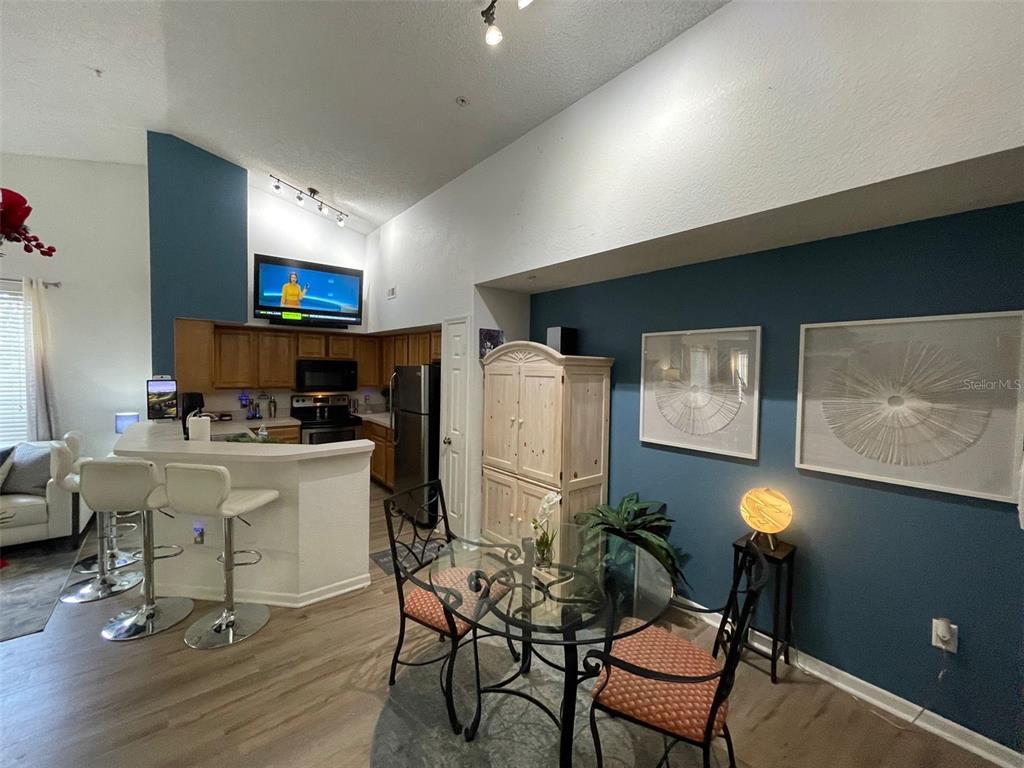 A kitchen with a breakfast bar and dining area features blue walls and vaulted ceilings — 13103 MULBERRY PARK DRIVE UNIT 831, ORLANDO, FL