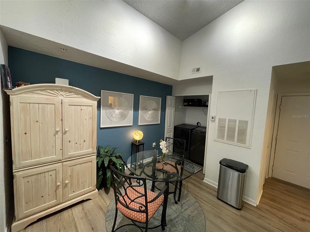 A dining area features a glass table, metal chairs, a blue accent wall, and laundry closet — 13103 MULBERRY PARK DRIVE UNIT 831, ORLANDO, FL