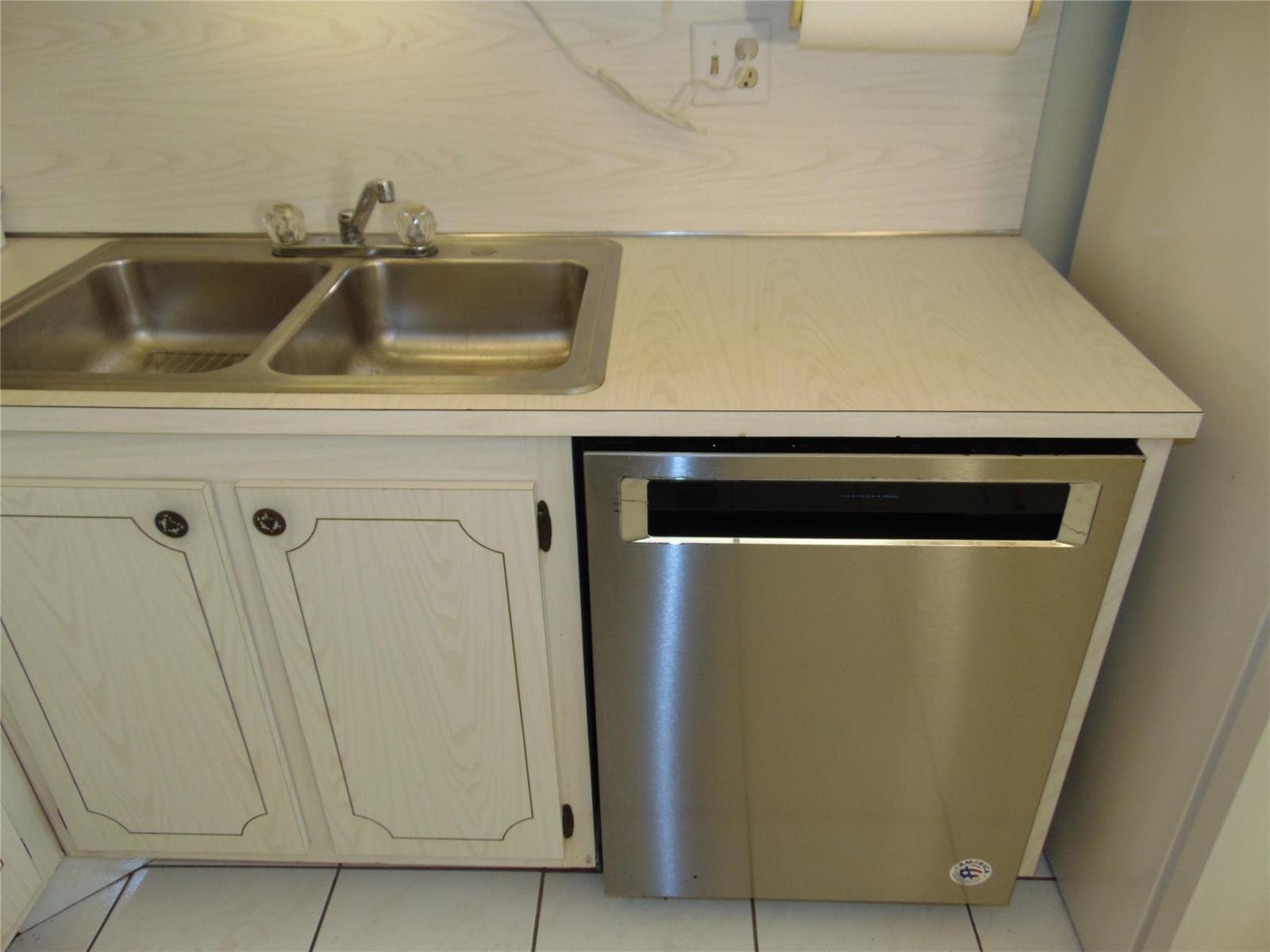 A kitchen sink and stainless steel dishwasher are set into a light-colored laminate countertop — 9788 Marina Boulevard # 313, Boca Raton FL 33428, BOCA RATON, FL