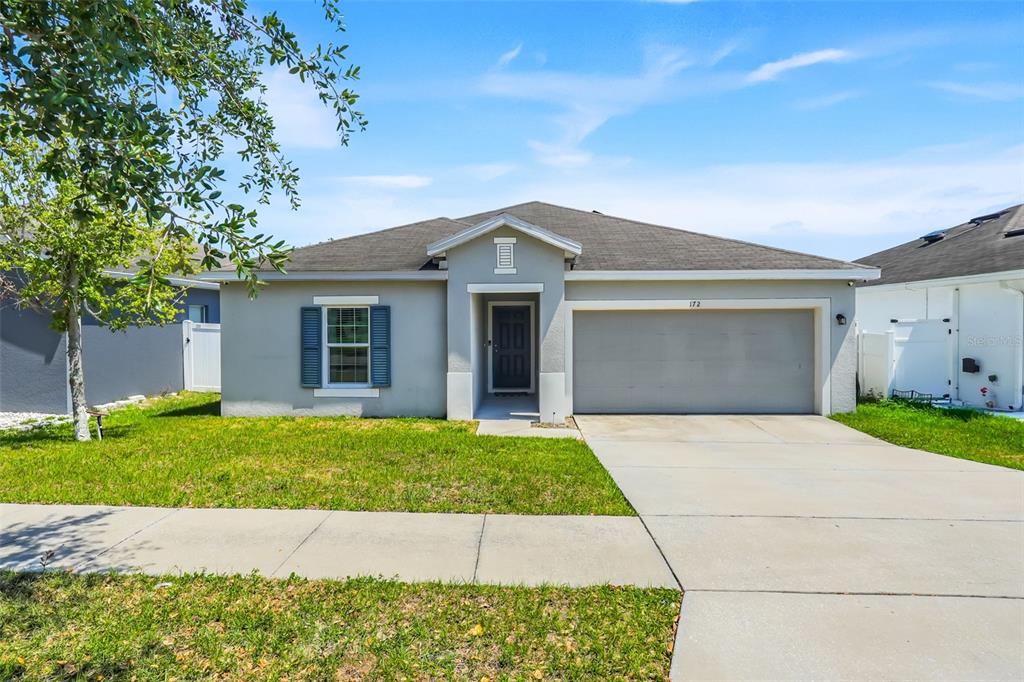 A single-story house with a gray exterior, a two-car garage, and a front lawn — 172 TANAGER STREET, HAINES CITY, FL