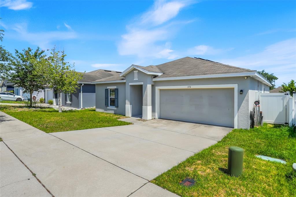 A single-story house with a gray stucco exterior, a two-car garage, and a concrete driveway — 172 TANAGER STREET, HAINES CITY, FL