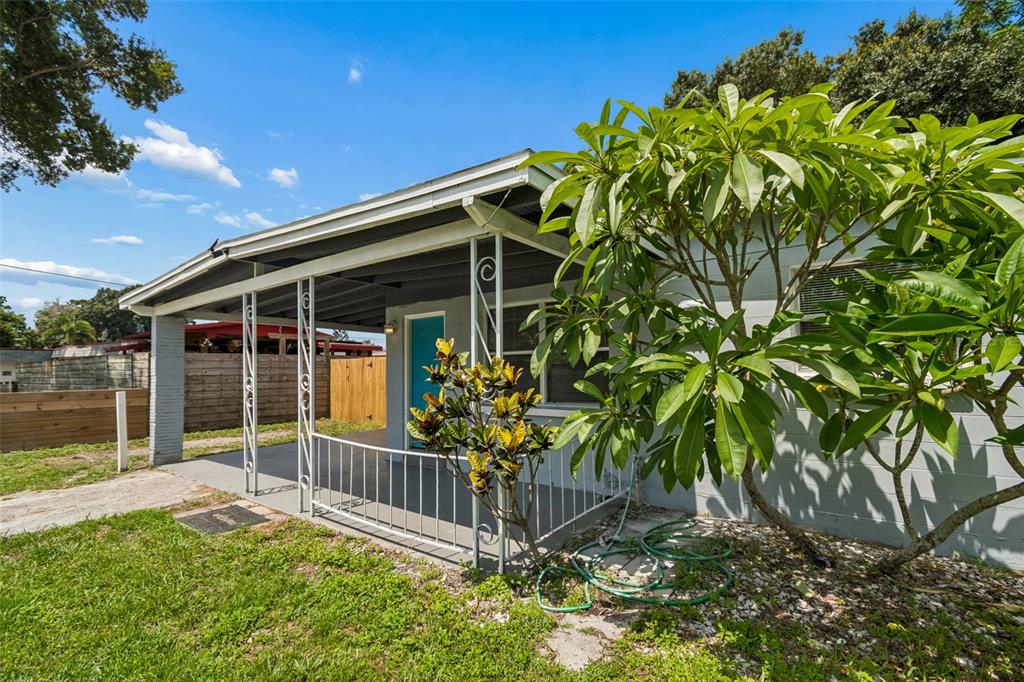 A covered concrete patio with white metal railings sits beside a house with a tree — 11136 104TH STREET, LARGO, FL