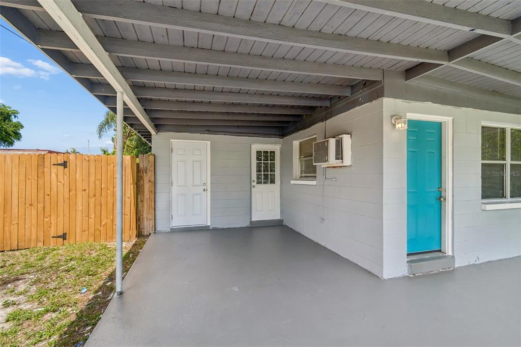 A covered concrete patio features a blue door, two white doors, and a window unit — 11136 104TH STREET, LARGO, FL