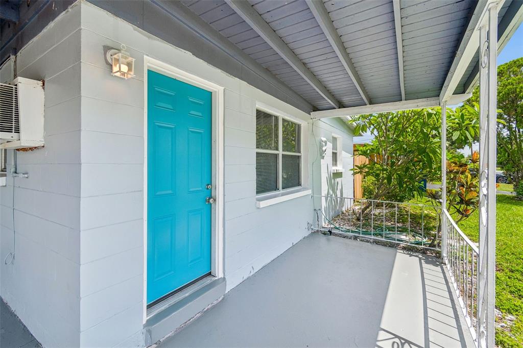 A light blue house exterior features a bright turquoise front door and a covered porch — 11136 104TH STREET, LARGO, FL