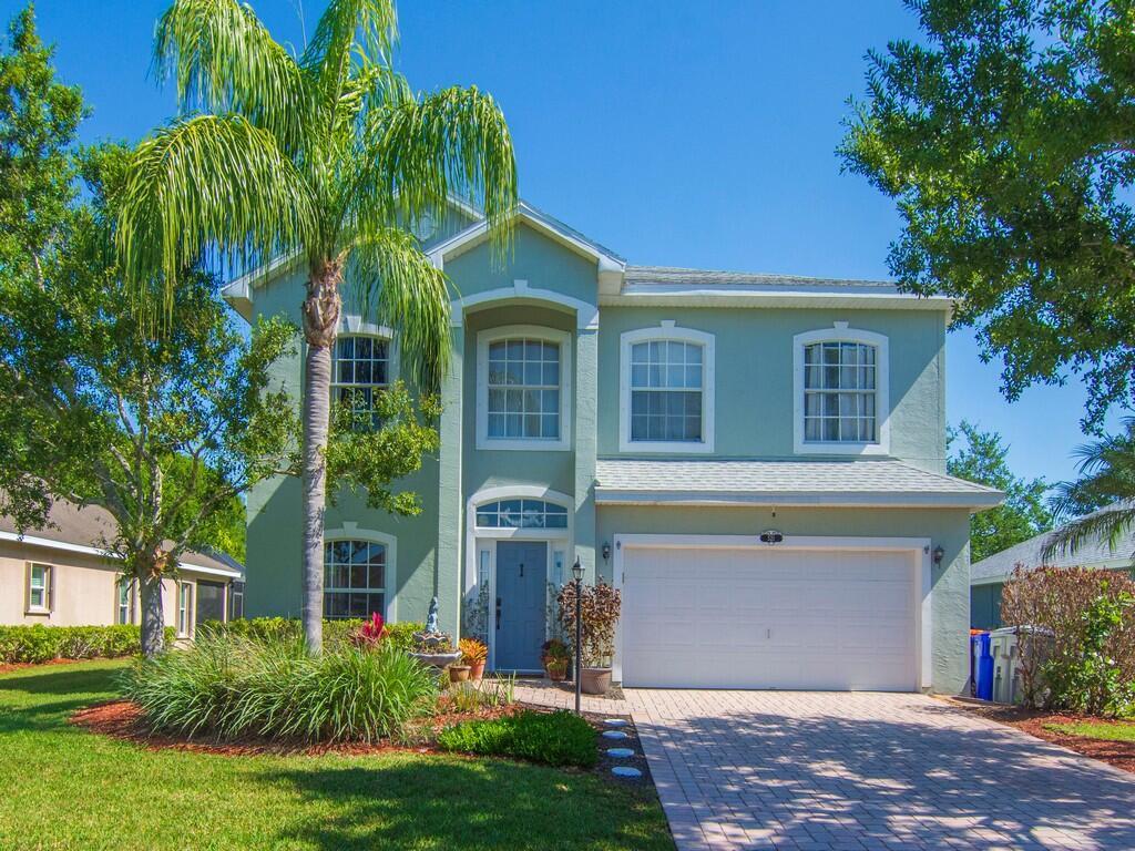 A two-story light green house with a white garage and a palm tree in front — 521 N Valencia Circle SW, Vero Beach FL 32968, VERO BEACH, FL